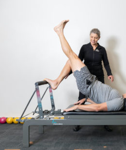 man stretching leg on pilates reformer